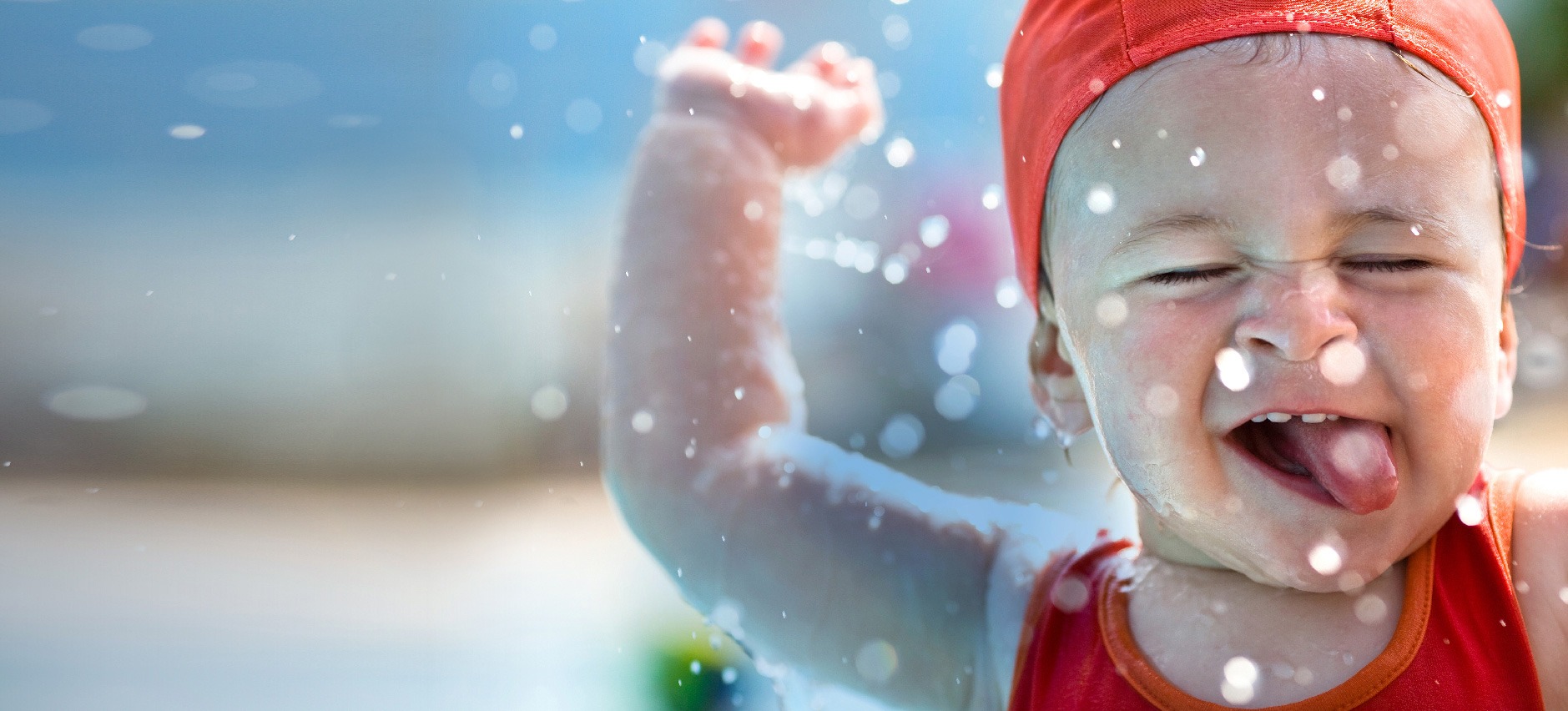 close up of smiling toddler boy with swim suit and cap playing in water