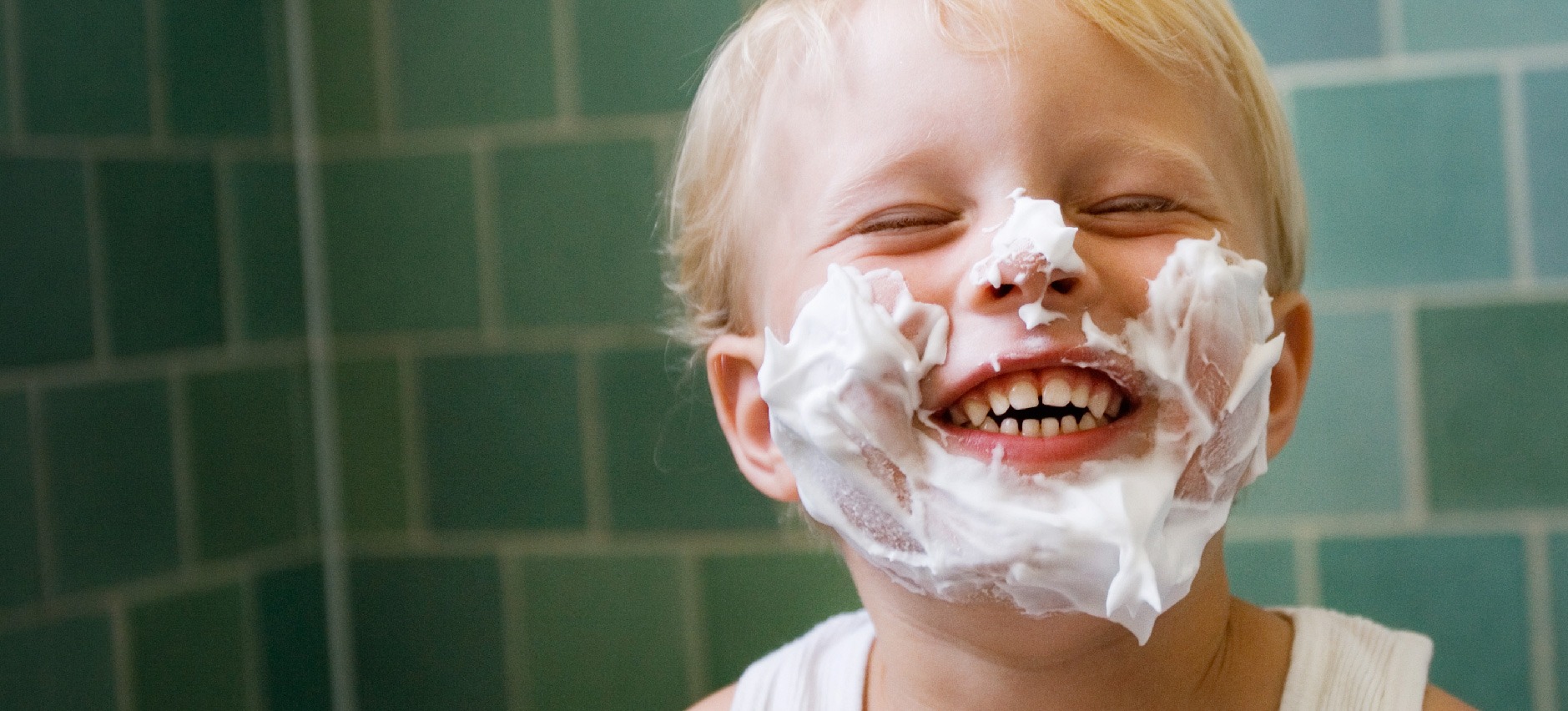 smiling toddler boy with shaving cream on face